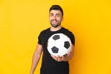 Futbol topuyla izole edilmiş sarı arka planda beyaz bir adam.