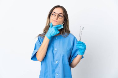 Romen kadın diş hekiminin elinde pembe arka planda izole edilmiş araçlar bulunuyor