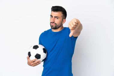 Yakışıklı genç futbolcu, izole edilmiş duvarın üzerinden başparmağıyla olumsuz ifade gösteriyor.