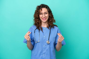 Genç beyaz kadın, mavi arka planda izole edilmiş para hareketi yapıyor.