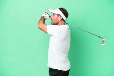 Yeşil arka planda golf oynayan orta yaşlı beyaz bir adam.