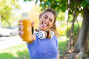 Açık havada portakal suyu tutan genç sarışın kadın.