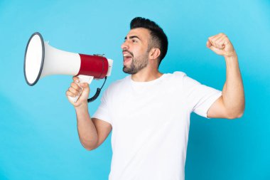 İzole edilmiş mavi arka plan üzerinde beyaz bir adam megafondan bir şey duyurmak için bağırıyor.