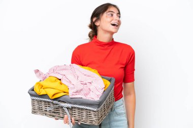 Young caucasian woman holding a clothes basket isolated on white background laughing