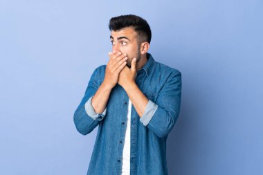 İzole edilmiş mavi arka planda beyaz bir adam ağzını kapatıyor ve yana bakıyor.