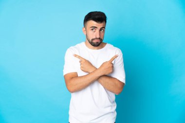 İzole edilmiş mavi arka planda beyaz bir adam. Yan taraftakilerin şüpheleri olduğunu gösteriyor.