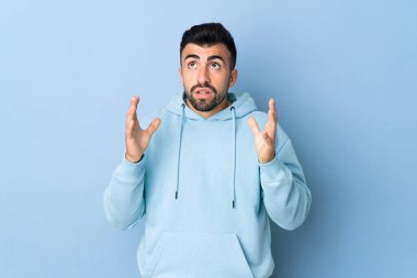 İzole edilmiş mavi arka planda beyaz bir adam bunalımda.