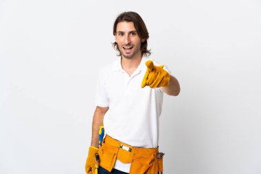 Tecrit edilmiş arka planda genç elektrikçi şaşırmış ve ön tarafı işaret ediyor.