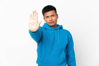 Beyaz arka planda izole edilmiş genç Ekvadorlu adam dur hareketi yapıyor.