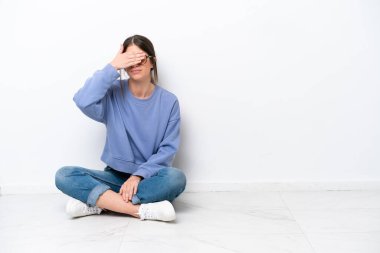 Beyaz arka planda, elleri ve gözleri kapalı, yerde yalnız oturan beyaz bir kadın. Bir şey görmek istemiyorum.