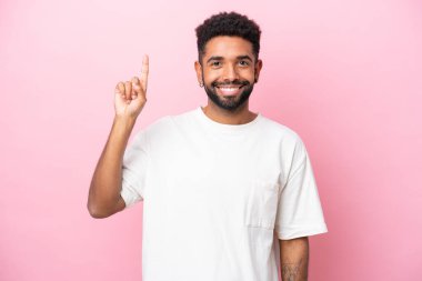 Pembe arka planda izole edilmiş genç Brezilyalı adam harika bir fikre işaret ediyor.