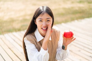 Dışarıda elmalı genç bir Çinli kadın bir şeyler fısıldıyor.