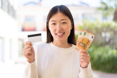 Dışarıdaki güzel Çinli kadın mutlu bir ifadeyle bir sürü para alıyor.