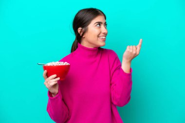 Mavi arka planda bir kase mısır gevreği tutan beyaz bir kadın çözümün farkına varmak için parmağını kaldırıyor.