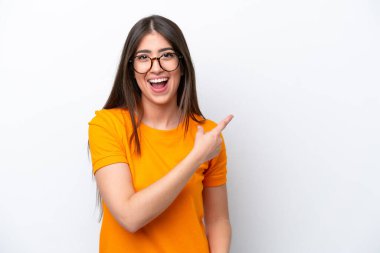 Beyaz arka planda izole edilmiş genç beyaz kadın şaşırmış ve işaret ediyor.