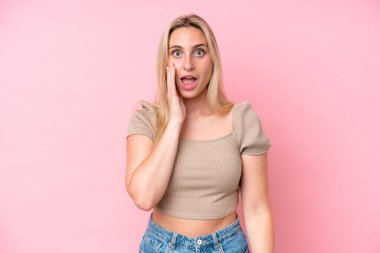 Pembe arka planda izole edilmiş beyaz bir kadın. Şaşırmış ve şok olmuş bir yüz ifadesi var.