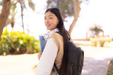 Dışarıdaki güzel Çinli kadın elinde mutlu bir ifadeyle bir defter tutuyor.