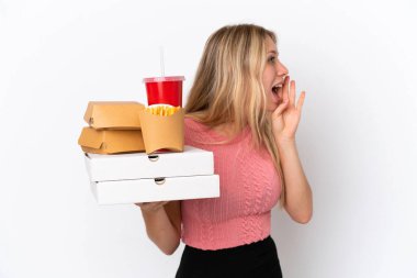 Mavi arka planda yağlı yiyecekler tutan beyaz bir kadın ağzı sonuna kadar açık bağırıyor.