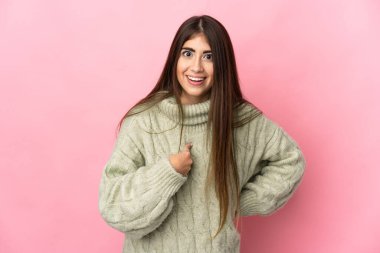 Pembe arka planda yalıtılmış beyaz bir kadın. Şaşırtıcı bir yüz ifadesi var.