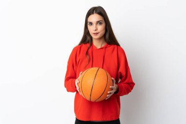 Beyaz arka planda basketbol oynayan beyaz tenli genç kadın.