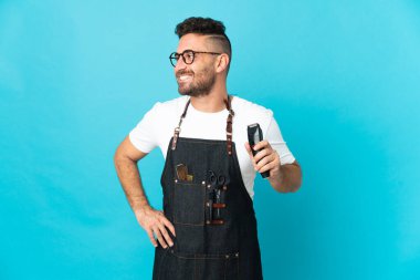 Önlüklü berber kolları kalçasında ve gülümsüyor.