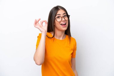 Beyaz arka planda izole edilmiş genç beyaz kadın parmaklarıyla tamam işareti gösteriyor.