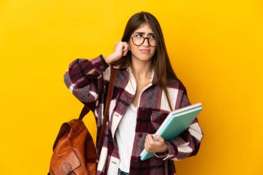 Sarı arka planda izole edilmiş genç bir bayan hayal kırıklığına uğramış ve kulaklarını kapatmış.