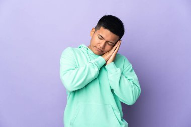 Genç Ekvador 'lu, mor arka planda izole edilmiş bir adam uyku jesti yapıyor.