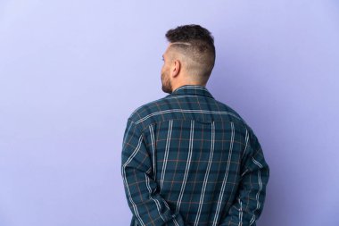 Beyaz adam mor arka planda izole edilmiş ve arkasına bakıyor.