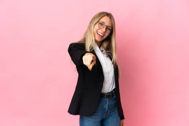 İş sarışını bir kadın pembe arka planda izole edilmiş, mutlu bir ifadeyle öne bakıyor.