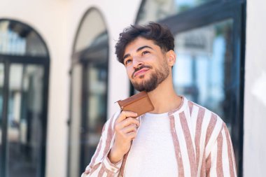 Açık havada cüzdan tutan yakışıklı bir Arap.