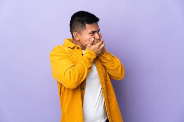 Genç Ekvadorlu adam mor arka planda izole edilmiş ağzını kapatıyor ve yan tarafa bakıyor.