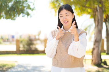 Dışarıdaki güzel Çinli kadın ön tarafı gösteriyor ve gülümsüyor.