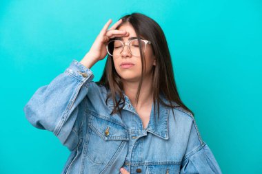 Güzel genç bir kadın mavi arka planda yalnız poz veriyor.    