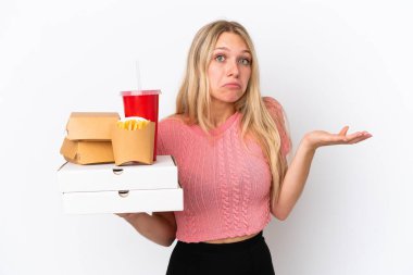 Mavi arka planda yağlı yiyecekler tutan beyaz bir kadın. Kuşkuları var ve ellerini kaldırıyor.