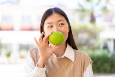 Dışarıdaki güzel Çinli kadın elinde elma tutuyor.