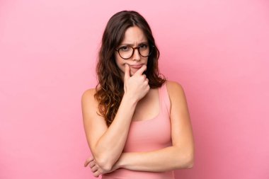 Pembe arka planda izole edilmiş beyaz bir kadın. Şüpheleri var.