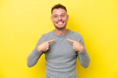 Sarı arka planda yalıtılmış, yüzü şaşırmış, beyaz, yakışıklı genç bir adam.