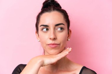 Pembe arka planda izole edilmiş beyaz kadın bale yapıyor.