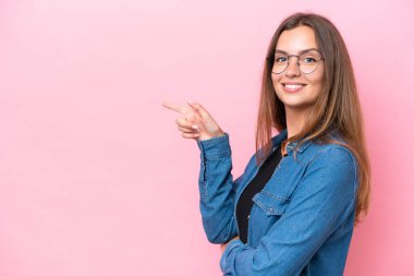 Pembe arka planda izole edilmiş genç beyaz bir kadın.