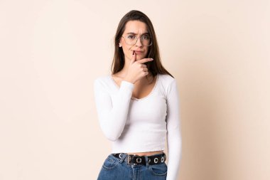 Tecrit edilmiş bej arka plan düşünen genç bir kadın.