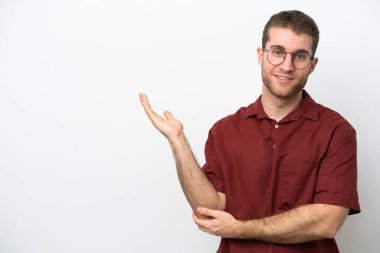 Beyaz arka planda soyutlanmış beyaz tenli genç adam davet edilmek için ellerini yana uzatıyor.