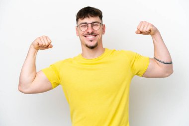 Beyaz arka planda izole edilmiş beyaz, yakışıklı genç bir adam güçlü bir jest yapıyor.