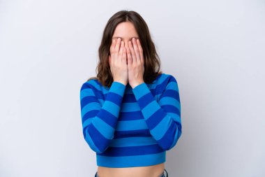 Beyaz arka planda izole edilmiş beyaz tenli genç bir kadın gözlerini elleriyle kapatıyor.