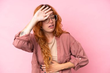 Pembe arka planda gözlüklü ve yorgun genç beyaz kadın.