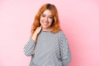 Pembe arka planda izole edilmiş genç beyaz kadın gülüyor.