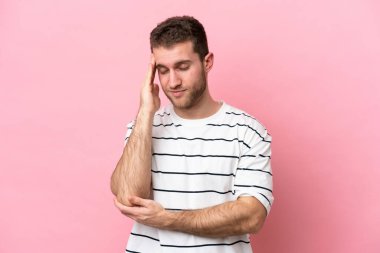 Kafkasyalı genç adam pembe arka planda izole edilmiş, baş ağrısı var.