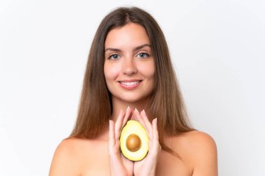 Beyaz arka planda izole edilmiş beyaz bir kadın elinde bir avokado tutarken gülümsüyor. Portreyi kapat