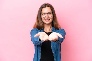 Pembe arka planda izole edilmiş genç beyaz kadın bir ilan vermek için avucunun içinde hayali bir fotokopi makinesi tutuyor.