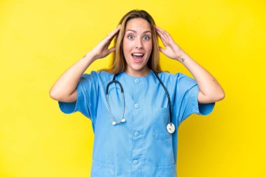 Sarı arka planda izole edilmiş genç cerrah kadın. Sürpriz bir ifadeyle.